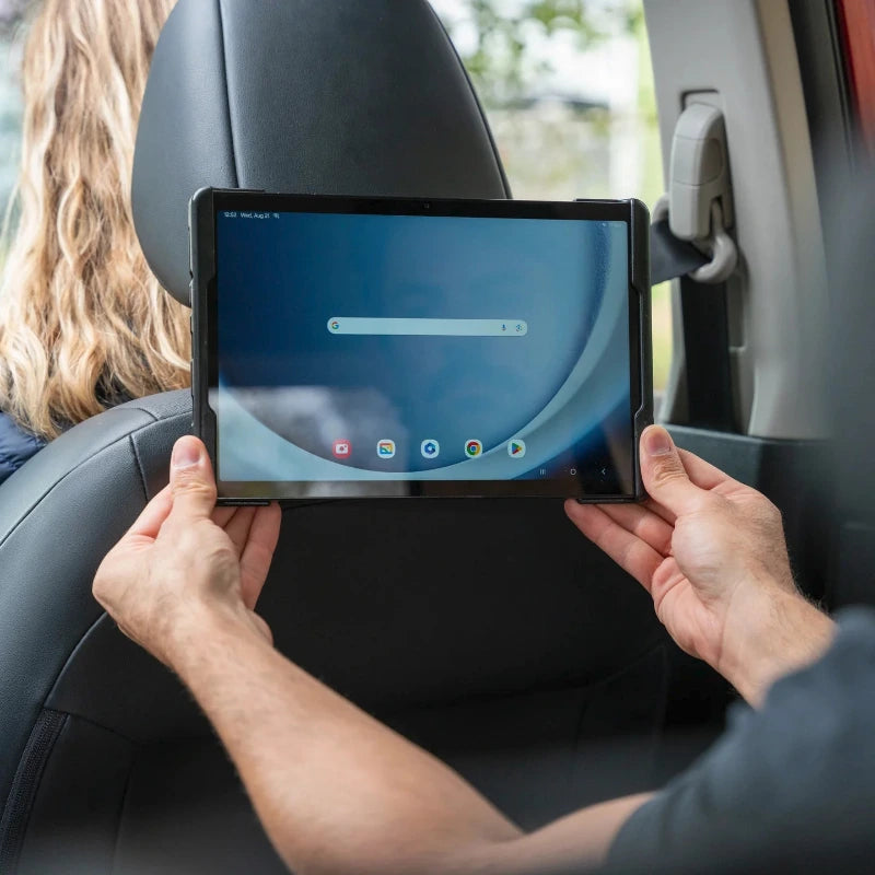 Person using a tablet in a car, with the tablet mounted using a RAM cradle to the vehicle headrest